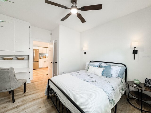 bedroom with light wood-type flooring, freestanding refrigerator, and a ceiling fan