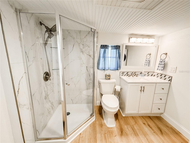 bathroom with toilet, wood finished floors, vanity, baseboards, and a marble finish shower