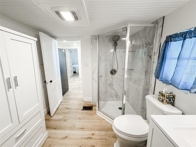 full bathroom with toilet, a marble finish shower, wood finished floors, and visible vents