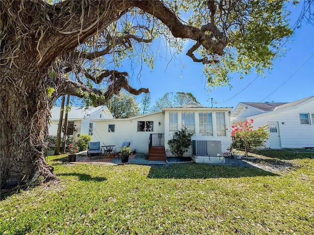 rear view of property featuring a patio, central AC unit, a lawn, and stucco siding