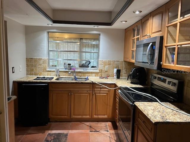 kitchen featuring a sink, stainless steel appliances, decorative backsplash, and light stone countertops