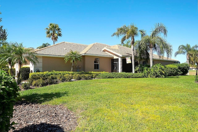 view of front facade featuring stucco siding, a tiled roof, and a front yard