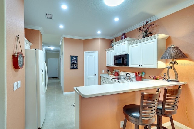 kitchen with visible vents, a breakfast bar, white appliances, a peninsula, and crown molding