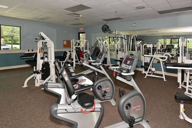 gym featuring a drop ceiling and baseboards