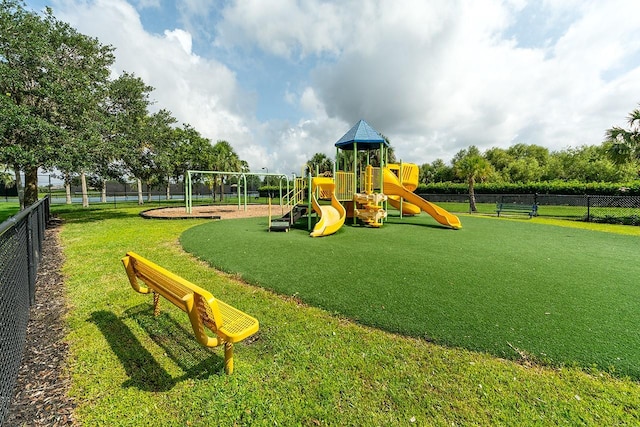 communal playground featuring fence and a lawn