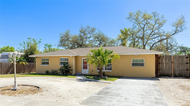 single story home with a gate, driveway, fence, and stucco siding