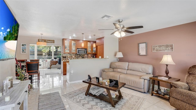 living area featuring a ceiling fan, visible vents, and light tile patterned flooring