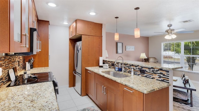 kitchen with stainless steel appliances, a peninsula, a sink, visible vents, and brown cabinets