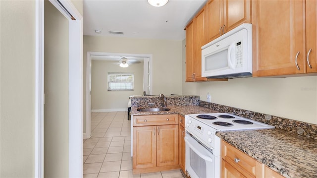 kitchen featuring white appliances, stone countertops, light tile patterned floors, a ceiling fan, and a sink