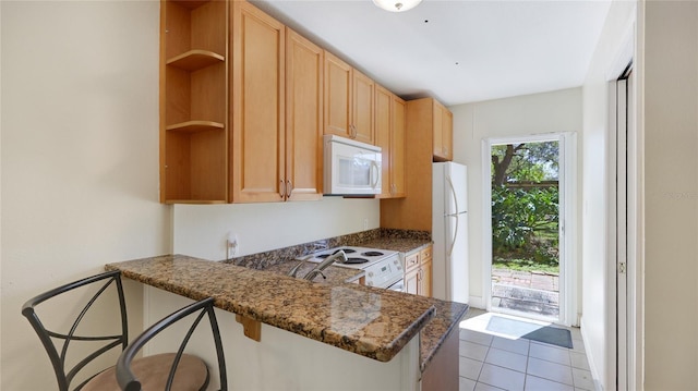 kitchen with light tile patterned floors, a peninsula, white appliances, open shelves, and a kitchen bar