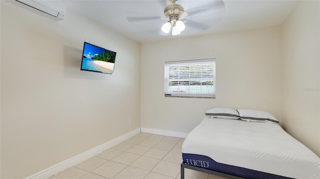 bedroom with a ceiling fan, a wall unit AC, baseboards, and light tile patterned flooring