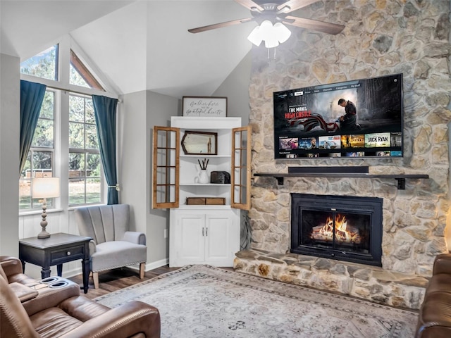 living area featuring lofted ceiling, a fireplace, wood finished floors, a ceiling fan, and baseboards