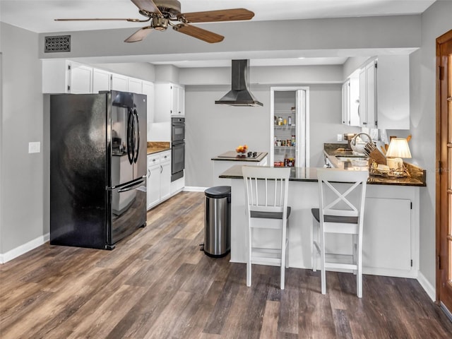 kitchen featuring dark countertops, dark wood-style flooring, a peninsula, extractor fan, and black appliances