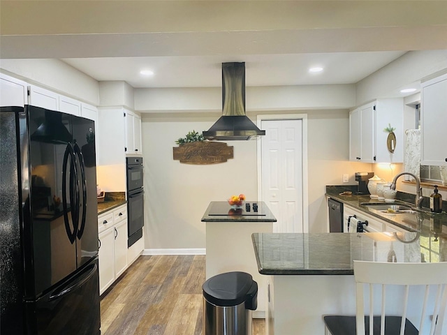 kitchen featuring a kitchen island, a sink, island range hood, wood finished floors, and black appliances