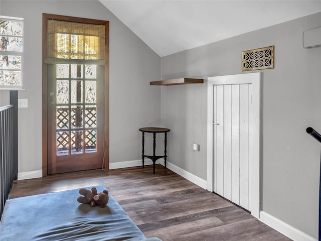 foyer featuring vaulted ceiling, plenty of natural light, wood finished floors, and baseboards