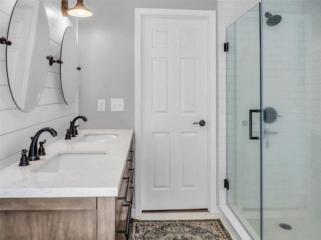 bathroom with double vanity, a sink, a shower stall, and tile patterned floors