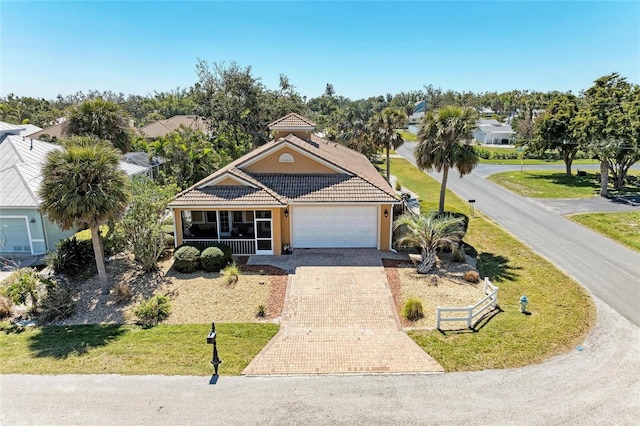 417 Tortuga Dr, Nokomis, FL 34275 - view of front of home with a tiled roof, an attached garage, decorative driveway, a front lawn, and stucco siding