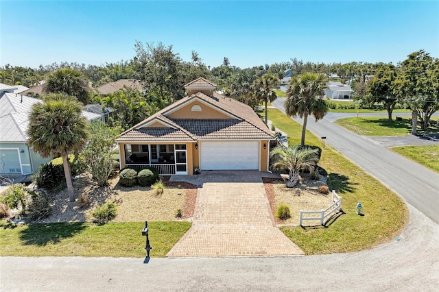 view of front of home with a tiled roof, an attached garage, decorative driveway, a front lawn, and stucco siding