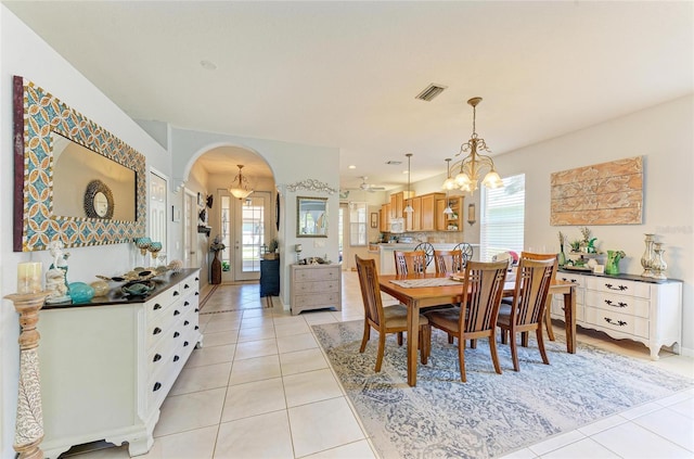 dining space featuring arched walkways, visible vents, a notable chandelier, and light tile patterned floors