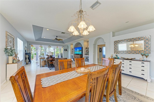 dining space with arched walkways, light tile patterned floors, a raised ceiling, visible vents, and ceiling fan with notable chandelier