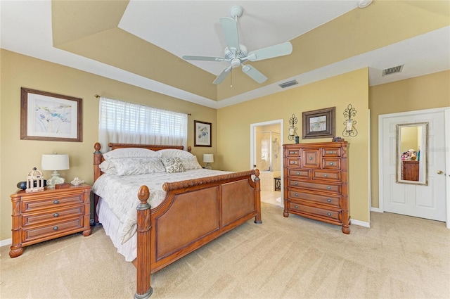 bedroom with light carpet, visible vents, and a tray ceiling