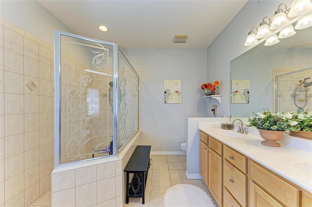 bathroom featuring tile patterned flooring, toilet, a sink, tiled shower, and double vanity