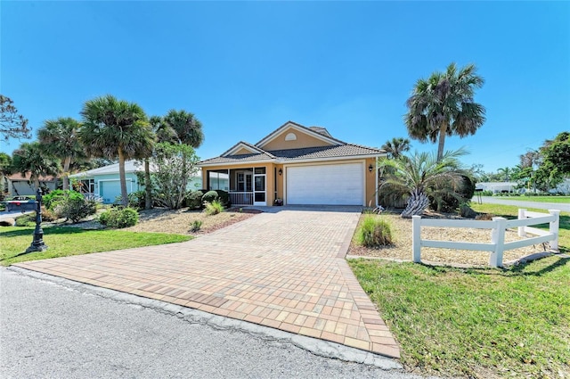 view of front of property featuring an attached garage, fence, decorative driveway, stucco siding, and a front yard