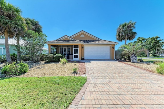 single story home with a tiled roof, an attached garage, decorative driveway, a front lawn, and stucco siding