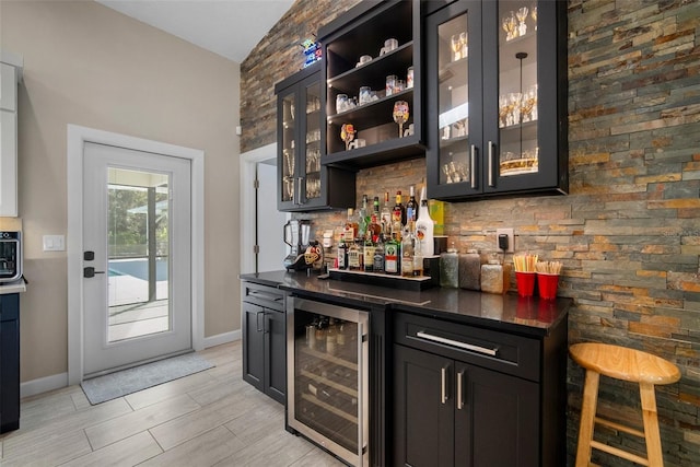 bar featuring a bar, wine cooler, baseboards, and tasteful backsplash