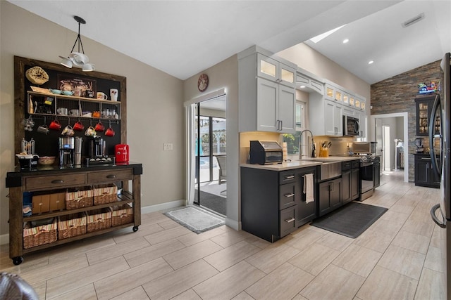 kitchen featuring stainless steel microwave, visible vents, light countertops, vaulted ceiling, and a sink