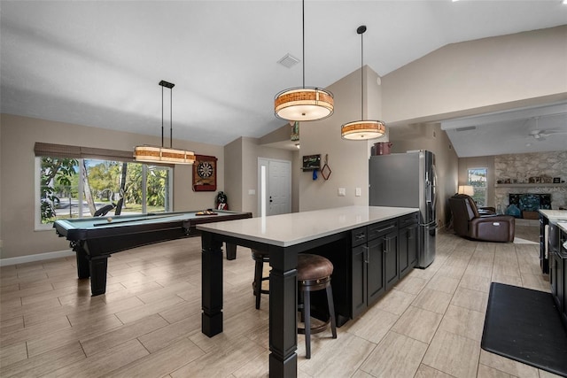 kitchen with visible vents, lofted ceiling, light countertops, stainless steel fridge, and a wealth of natural light