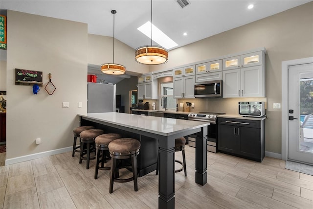 kitchen with lofted ceiling with skylight, a breakfast bar area, stainless steel appliances, and light countertops