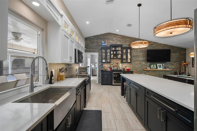 kitchen with a sink, wine cooler, white cabinets, light countertops, and vaulted ceiling