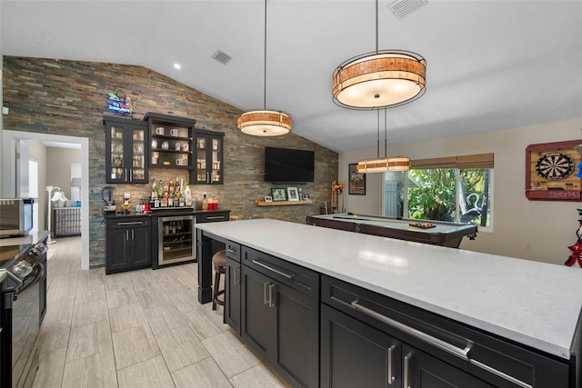 kitchen featuring decorative light fixtures, visible vents, beverage cooler, and vaulted ceiling