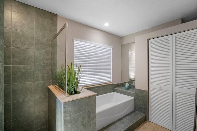 bathroom featuring tiled shower, a closet, tile patterned floors, a bath, and tile walls