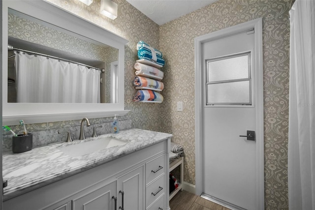 full bathroom with wallpapered walls, vanity, and wood finished floors