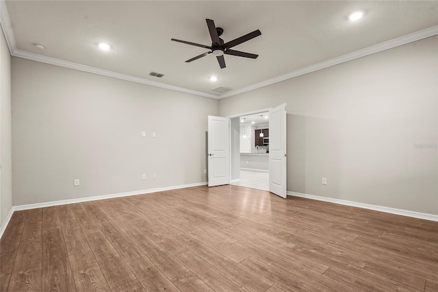 spare room featuring crown molding, visible vents, a ceiling fan, and wood finished floors