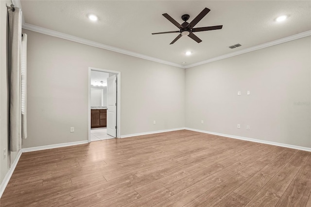 spare room with light wood-type flooring, ornamental molding, baseboards, ceiling fan, and visible vents