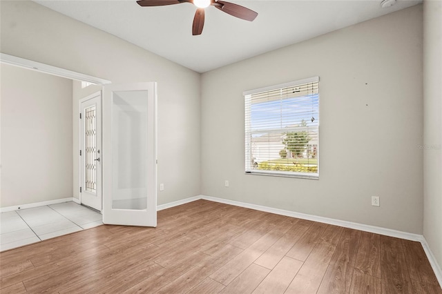 unfurnished room with a ceiling fan, baseboards, and light wood-style floors
