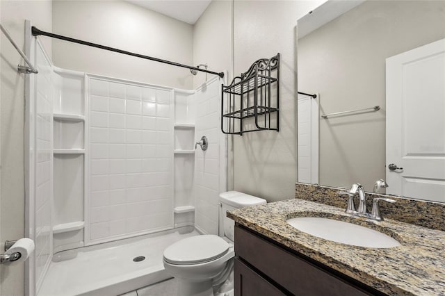 bathroom with toilet, a stall shower, and vanity