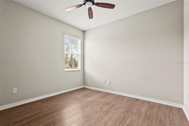 unfurnished room with wood finished floors, baseboards, and ceiling fan
