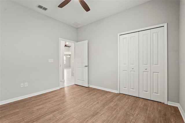 unfurnished bedroom with wood finished floors, baseboards, a closet, and visible vents