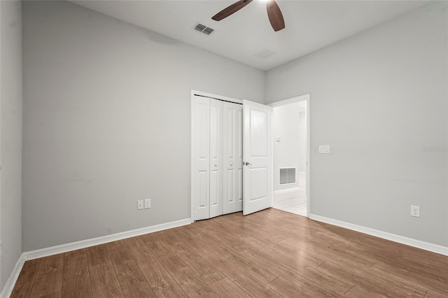 unfurnished bedroom with baseboards, visible vents, a closet, and wood finished floors