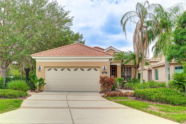 mediterranean / spanish-style home featuring stucco siding, concrete driveway, an attached garage, and a tiled roof