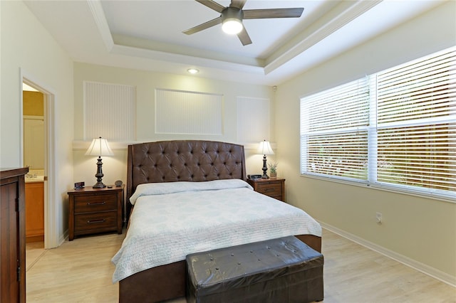 bedroom featuring light wood-type flooring, a raised ceiling, baseboards, and a ceiling fan