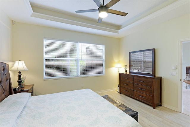 bedroom featuring a tray ceiling, baseboards, light wood-style flooring, and a ceiling fan