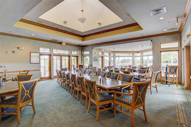 carpeted dining space with a tray ceiling, crown molding, and visible vents