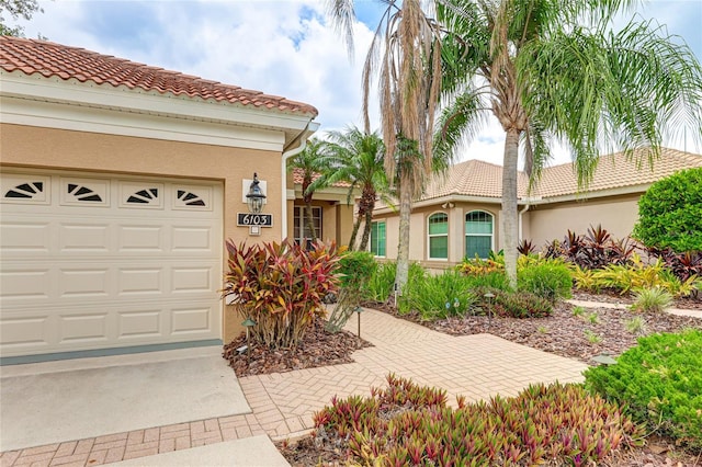 mediterranean / spanish-style home with a garage, a tile roof, and stucco siding