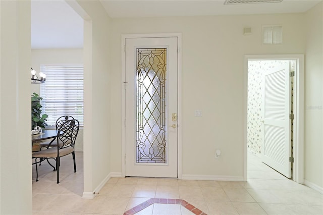 foyer entrance featuring an inviting chandelier, light tile patterned flooring, and baseboards