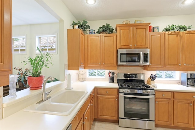 kitchen with appliances with stainless steel finishes, light countertops, and a sink